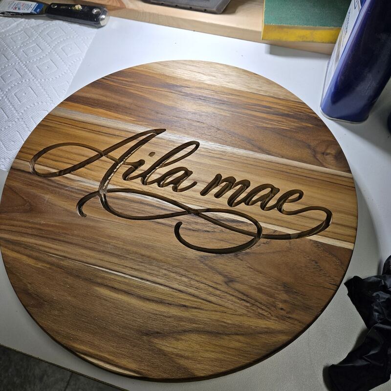Cursive name carved into a teak round